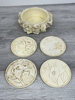Set of four coasters and matching floral holder displayed on table