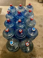 Top view of all 14 blue 5-gallon water bottles with caps
