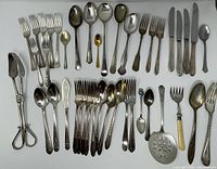 Entire lot laid out showing variety of flatware and serving items