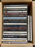 Box containing two stacks of CD cases with visible spines