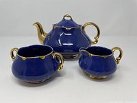 Front view of full three-piece tea set showing color and gold detailing