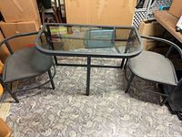 Glass-top metal patio table with two chairs front view