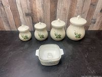 Group shot of four ceramic canisters and CorningWare casserole with lid
