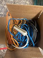 Top view of box showing assorted orange, blue, black cords and white power strip