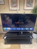 Front view of powered-on Panasonic 60-inch TV on stand showing Viera Connect menu