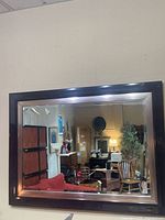 Front view of rectangular wall mirror showing dark brown wood frame with silver inner trim