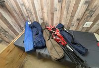 Five folded camping chairs in carry bags: blue, red, brown/tan