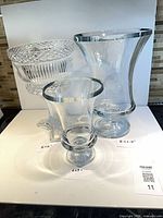 Three clear glass pieces: patterned pedestal bowl and two hurricane lamps