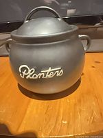 Front view showing Planters logo, crock shape and lid.