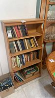 Front view of wooden bookshelf with four shelves, books shown but not included