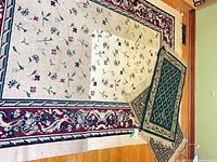 Large off-white floral area rug with two green accent mats on top