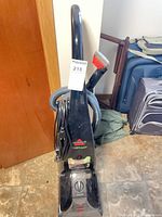 Full view of Bissell ProHeat upright carpet cleaner with hose and hand tool attached