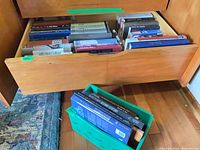 Drawer filled with military history books and separate green crate with large-format volumes