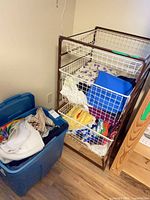 Blue plastic tote with fabrics beside three-basket wire storage unit