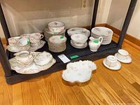 Full lot on shelving showing cups, saucers, plates, bowl, platters, creamer