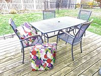 Patio table with four chairs and floral cushions on deck