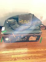 Front view of green trunk with ammo box and duffel on top
