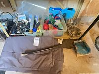 Overview of entire lot on shelf: toys bin, grooming clippers, bowls, cushion, rake