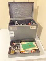 Open hard case with accessory trays showing bobbins, presser feet, booklet and notions