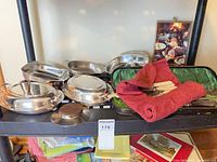 Group of silver plate and stainless serving dishes, red napkins, fitted case with utensils