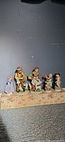 Group of five hand-painted ceramic child figurines with baskets lined up
