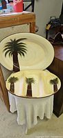 Both ceramic palm tree motif oval serving pieces: large platter and divided tray, front view.