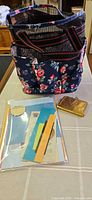 Tote bag, sewing kit compact and stationery pack displayed on tabletop