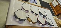 Seven pairs of sunglasses laid out on a table showing frame shapes, materials and lens colors