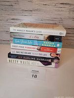 Stack of seven paperback books showing spines