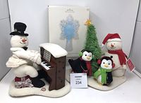 All three Hallmark items grouped: piano-playing snowman plush, Very Merry Trio plush, boxed snowflake tree topper