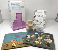 Group shot of Frida Mom box, wooden blocks, sign, two Charlie Brown books