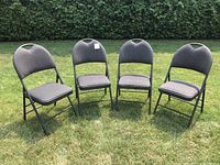Front view of four grey padded folding chairs on lawn