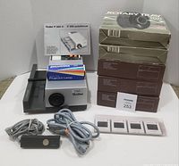 Full lot overview showing projector, stacked rotary trays, remote, bulb box and sample slides.