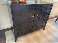 Full view of cabinet front showing geometric pattern, knobs, legs