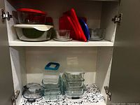 Cabinet shelves showing multiple glass containers, bowls and lids