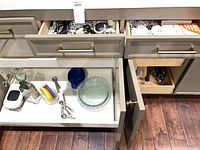 Open drawers and cabinet showing assorted utensils, glass pie dishes, juicer, grater, scale