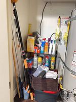 Overview of shelf with various cleaners, mop handles, bucket