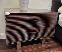 Front view of wood nightstand showing ribbed front and legs