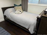 Full view of assembled dark wood twin daybed with bedding and pillows