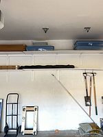 Hand truck leaning against wall showing full frame, handle and wheels