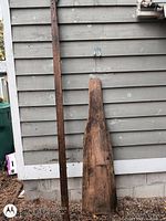 Full view of pole saw and ironing board leaning against siding