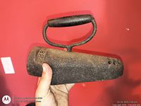 Full view of cast iron coal iron held in hand, showing overall form and handle