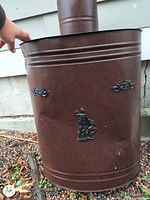 Front view showing full cylindrical chamber, surface rust, decorative cast iron details, attached pipe section