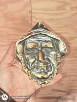 Front view of bronze cast face dish held in hand