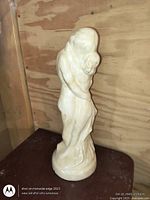 Full view of faux alabaster embracing couple sculpture on a table