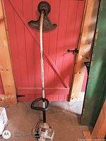 Full view of gas trimmer showing shaft, handle, guard