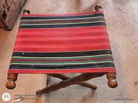 Top view of folding wooden stand showing striped fabric seat