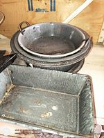 Rectangular grey enamel pan and stack of grey enamel bowls showing speckled pattern and wear