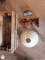 Top view showing wooden crate, milk glass shade, horse figurine, whisk, metal cup