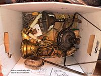 Top view of crate showing assorted brass and steel lamp parts, chains, canopies, sockets